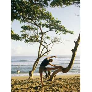  A Woman Stretches Her Body on a Small Tree at a Sandy 